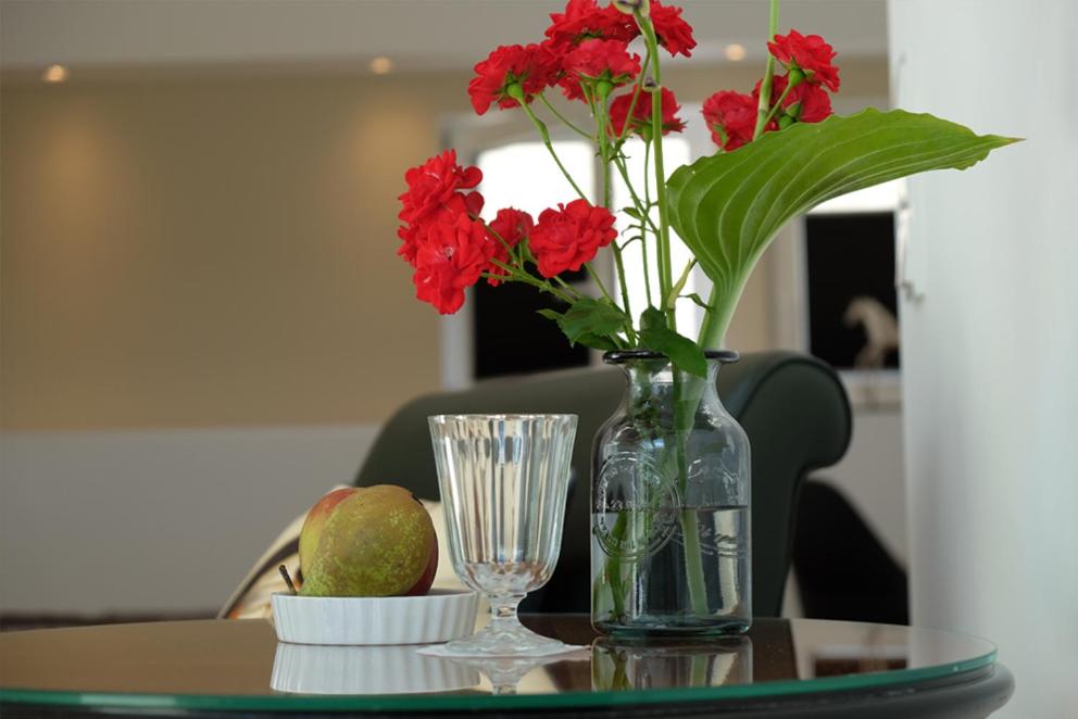 a glass vase with red flowers on a table at Alte Apotheke - Studio Appartements Karlsbad in Karlsbad