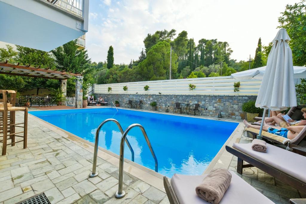 uma piscina com duas pessoas deitadas em cadeiras e um guarda-sol em Neda Hotel em Olympia