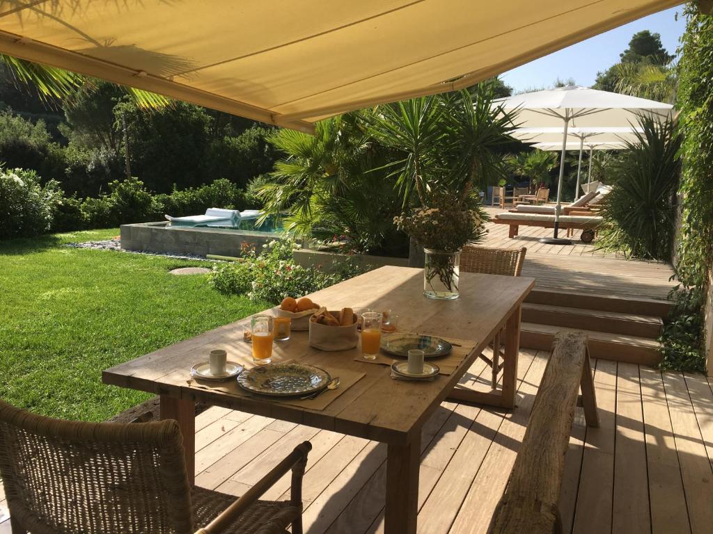 a wooden table and chairs on a deck with an umbrella at villa Sant-Anna in Saint-Tropez