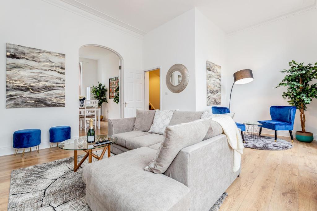 a living room with a couch and blue chairs at Bright & Spacious 4beds home - Kensington High Street-Olympia in London