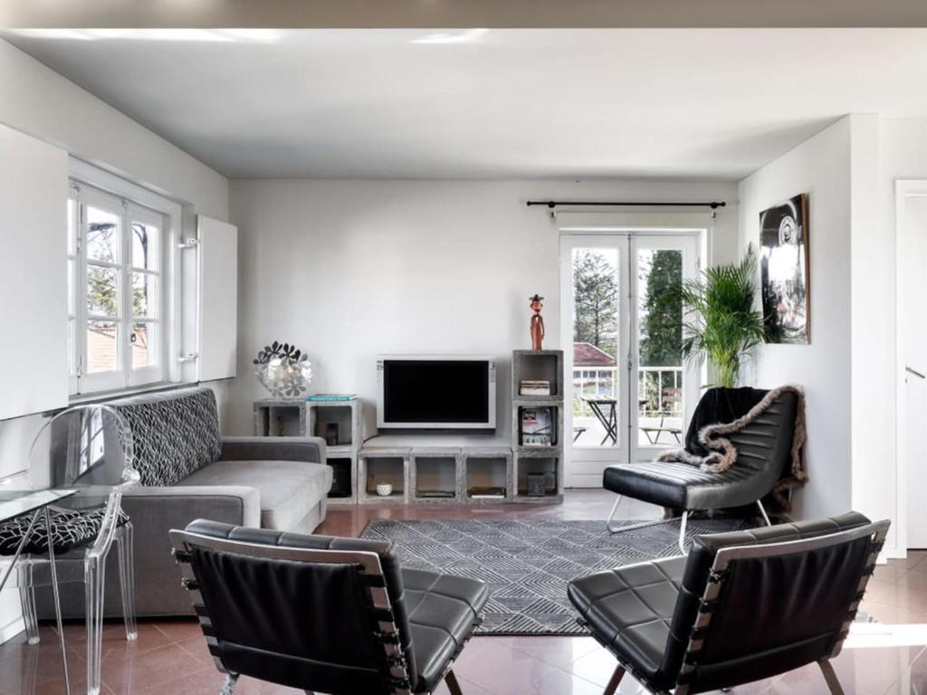a living room with a couch and chairs and a tv at Carcavelos Beach&Bike House (view, parking, wi-fi) in Carcavelos
