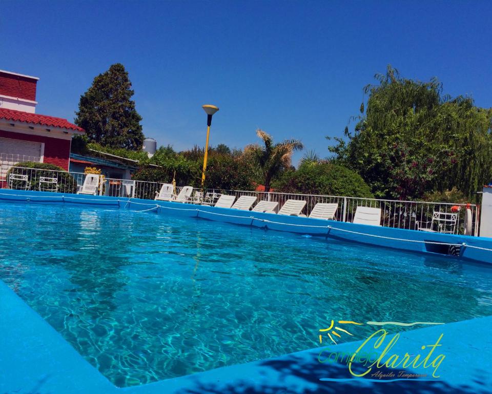a swimming pool with blue water and white chairs at Complejo Clarita in Villa Carlos Paz