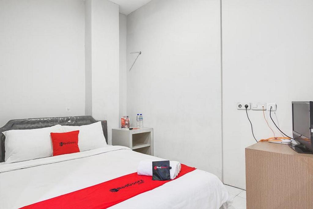 um quarto com uma cama com um cobertor vermelho em RedDoorz at Siwalankerto Surabaya em Surabaya