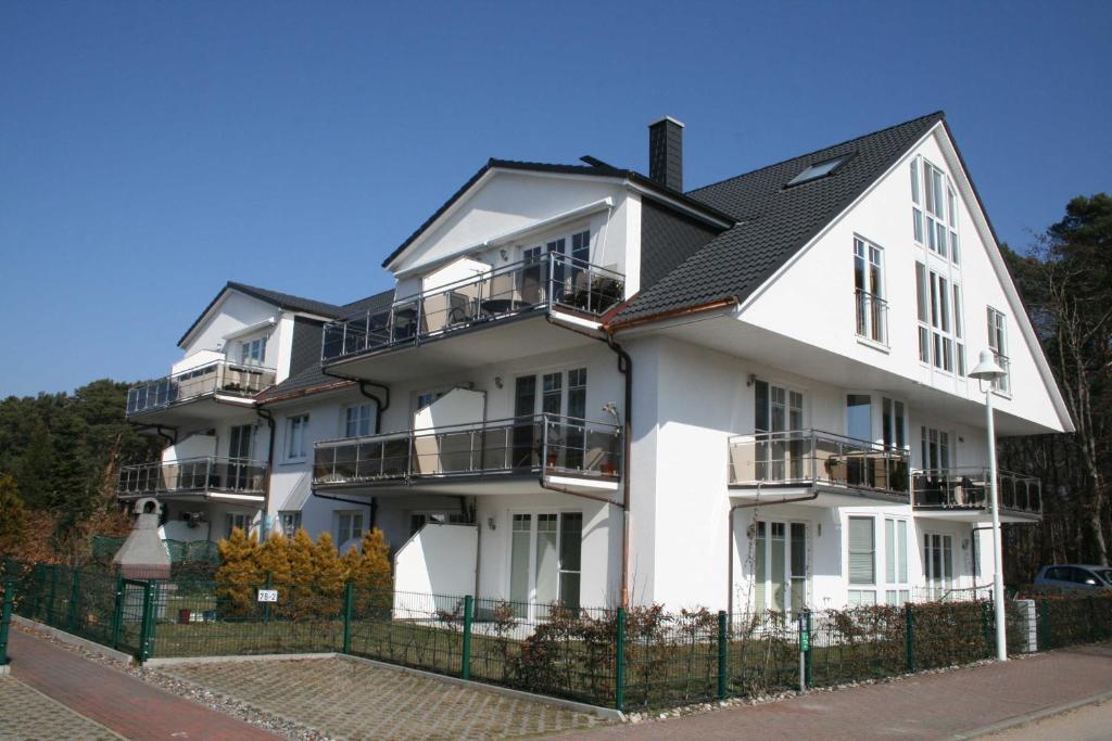 a white building with balconies and a fence at Ferienwohnung Sonnenstrand Whg 12 in Thiessow