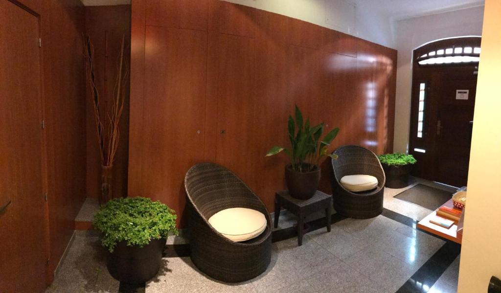 a lobby with three chairs and potted plants at Sitges Apartment in Sitges