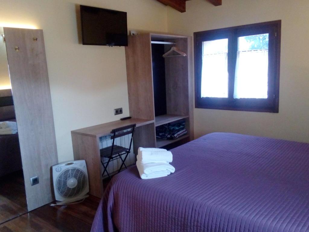 a bedroom with a bed with purple sheets and a window at CAN MENCIÓ - Plaça Major in Santa Pau