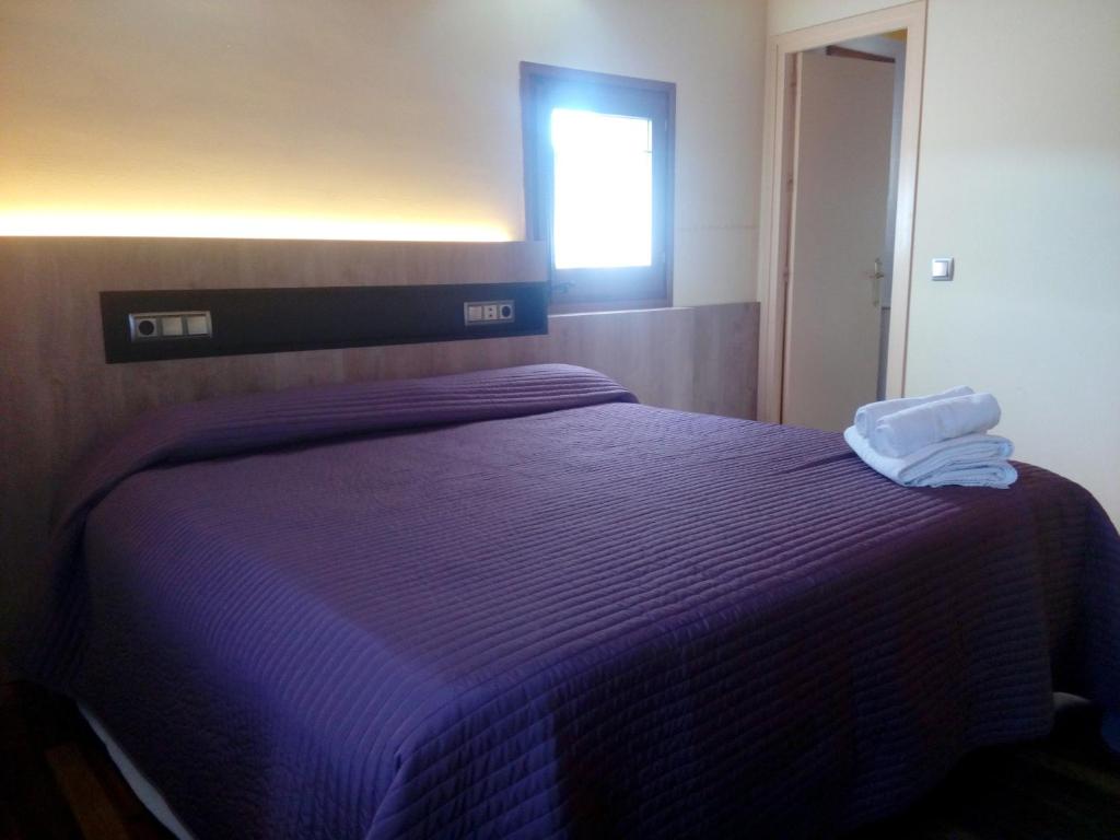 a purple bed with a towel on top of it at CAN MENCIÓ - Plaça Major in Santa Pau