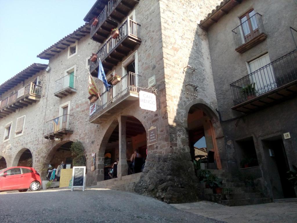a large stone building with balconies and a red car at CAN MENCIÓ - Plaça Major in Santa Pau