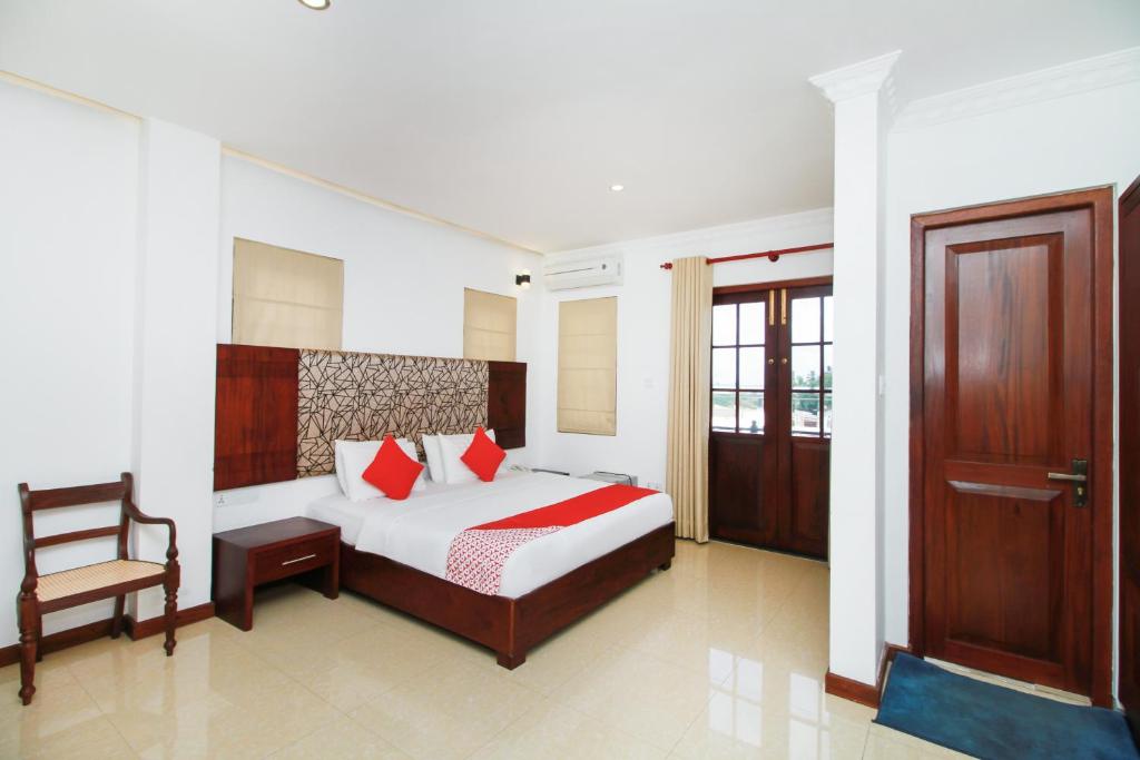 a bedroom with a bed and a chair and a door at Hotel Queensbury Malabe in Kaduwela