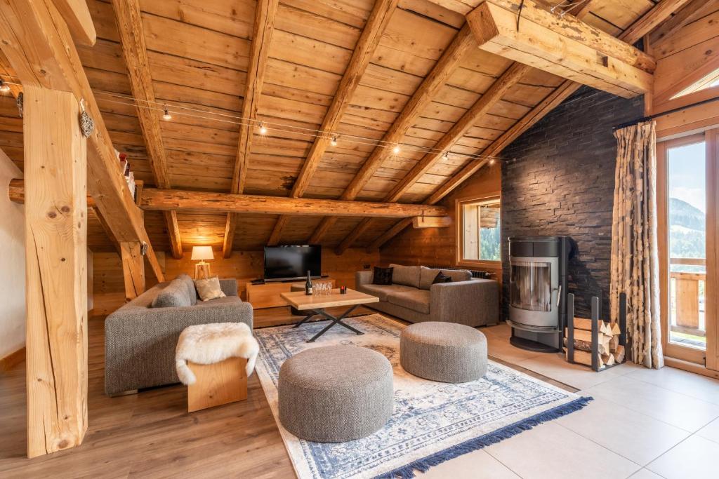 een woonkamer met een bank en stoelen en een tv bij Chalet l'Arolle in Les Gets