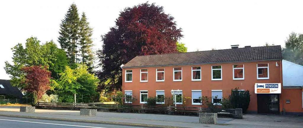 un grand bâtiment en briques sur le côté d'une rue dans l'établissement Pension Highway 3, à Bielefeld