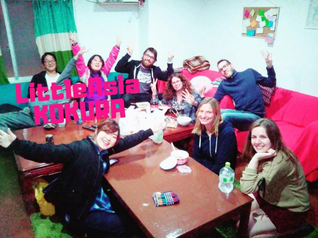 een groep mensen die rond een tafel zitten bij Fukuoka Guesthouse Little Asia Kokura in Kitakyushu