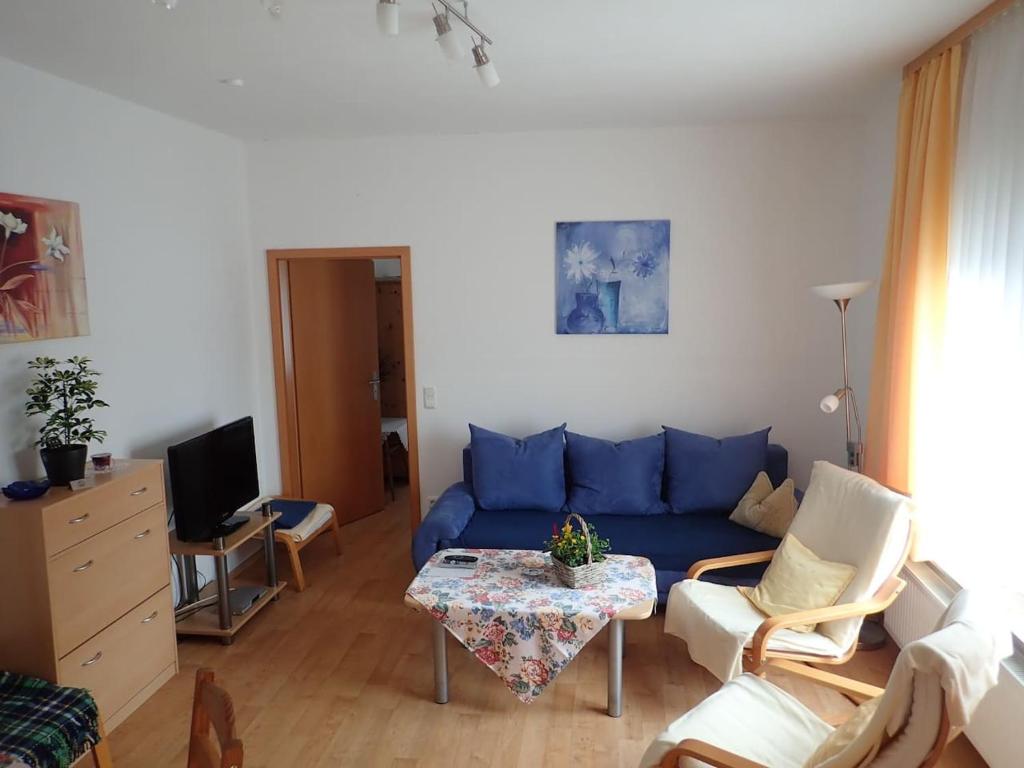 a living room with a blue couch and a table at Gemütliche Ferienwohnung in der Lüneburger Heide in Sprakensehl