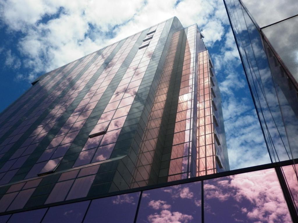 ein hohes Glasgebäude mit Spiegelung des Himmels in der Unterkunft Montresor Hotel Tower in Bussolengo
