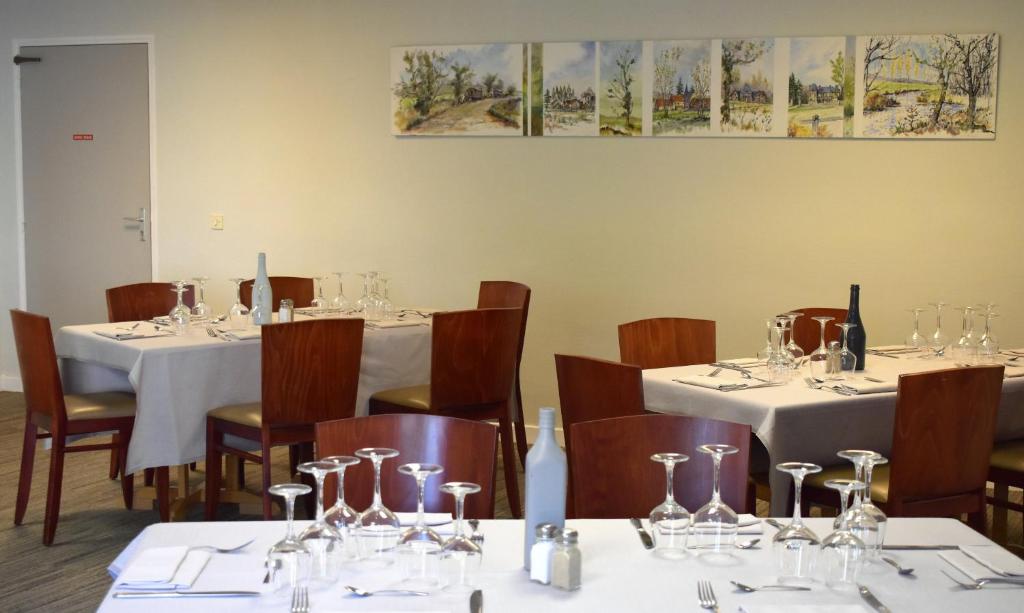 a dining room with tables and chairs with white tablecloths at Logis Hôtel Le Relais du Moulin in Valençay