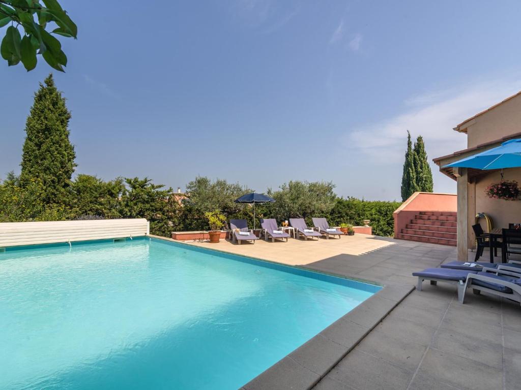 a large swimming pool with chairs and a house at Quiet villa with private pool in Caunes-Minervois