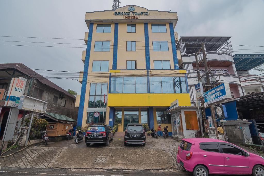 ein hohes Gebäude mit davor geparkt in der Unterkunft RedDoorz Syariah at Grand Taufiq Tarakan in Tarakan