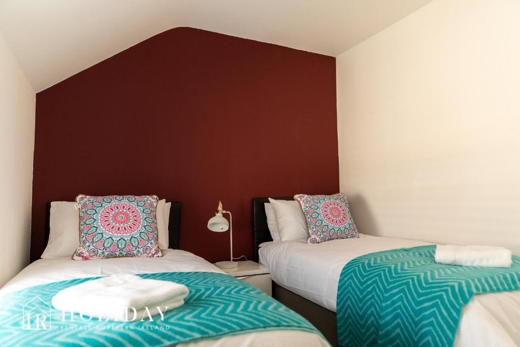 a bedroom with two beds and a brown wall at Portrush Penthouse in Portrush