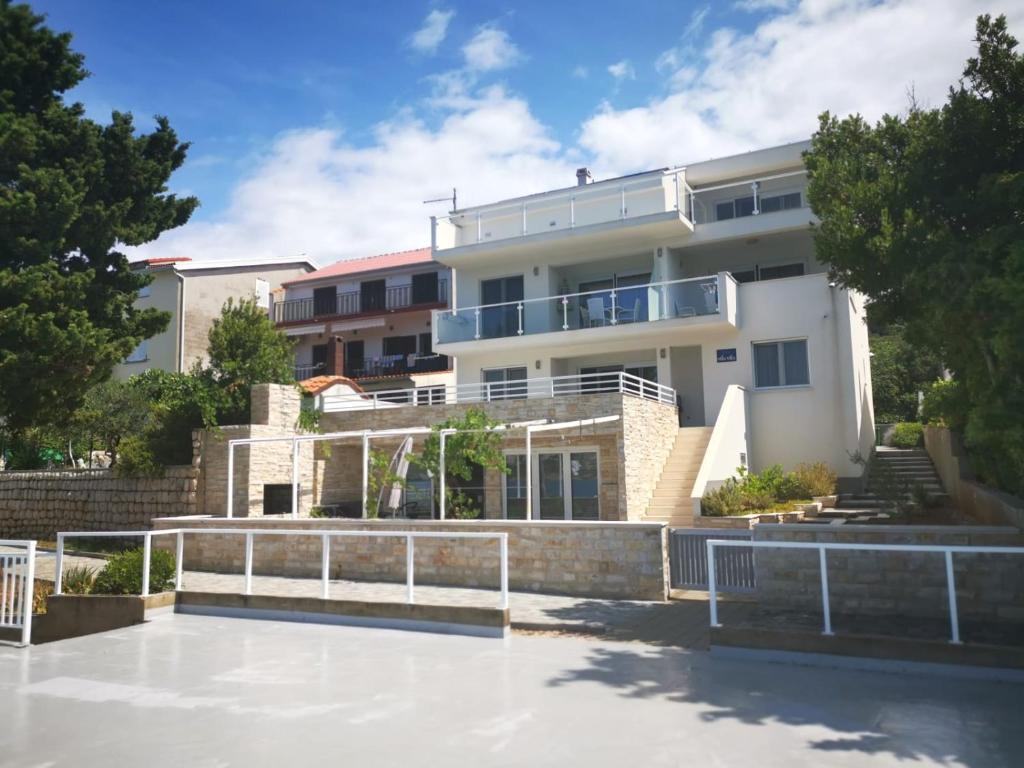 a large white building with a patio in front of it at Beachfront Apartments - Villa Vita in Stara Novalja