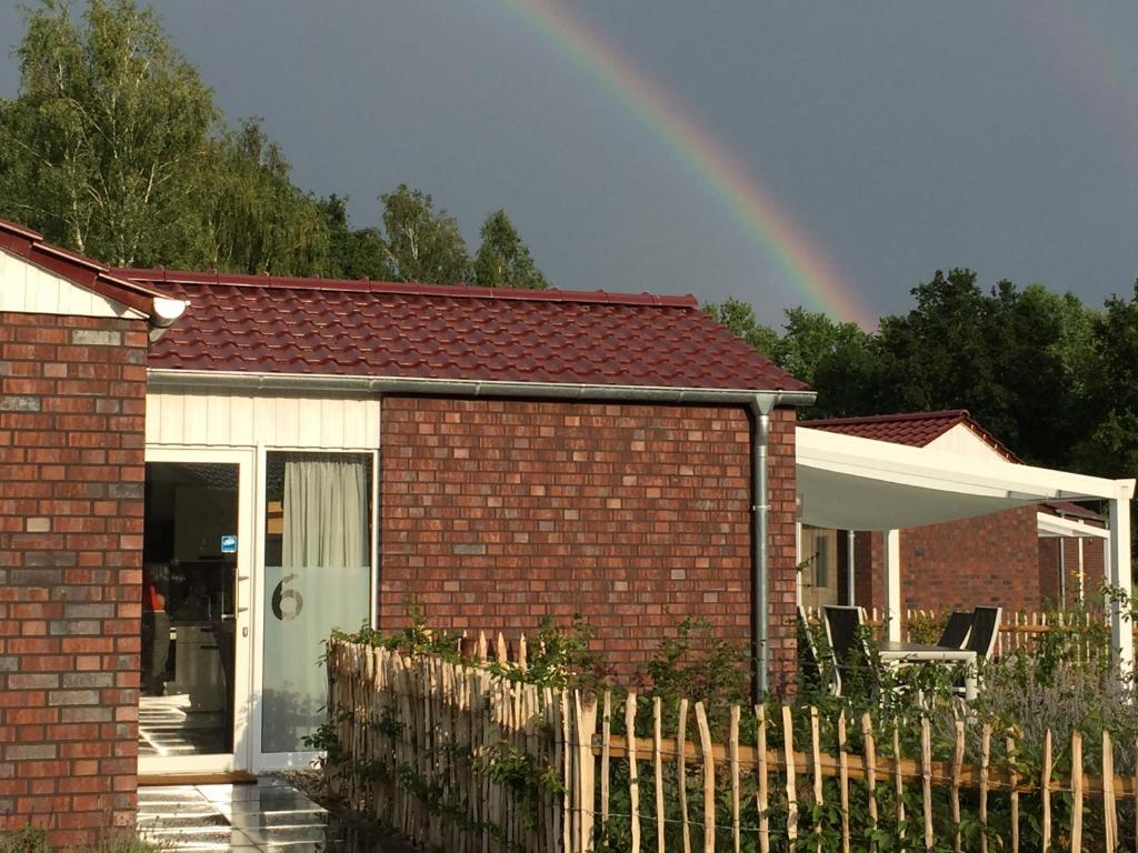 einen Regenbogen über einem Backsteinhaus mit einem Zaun in der Unterkunft Ferienhaus Nr 6 am Quendorfer See in Schüttorf