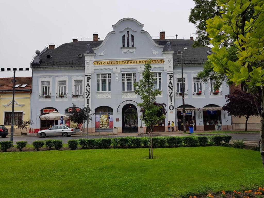 a large white building with a park in front of it at Kakukk Panzió in Nyírbátor