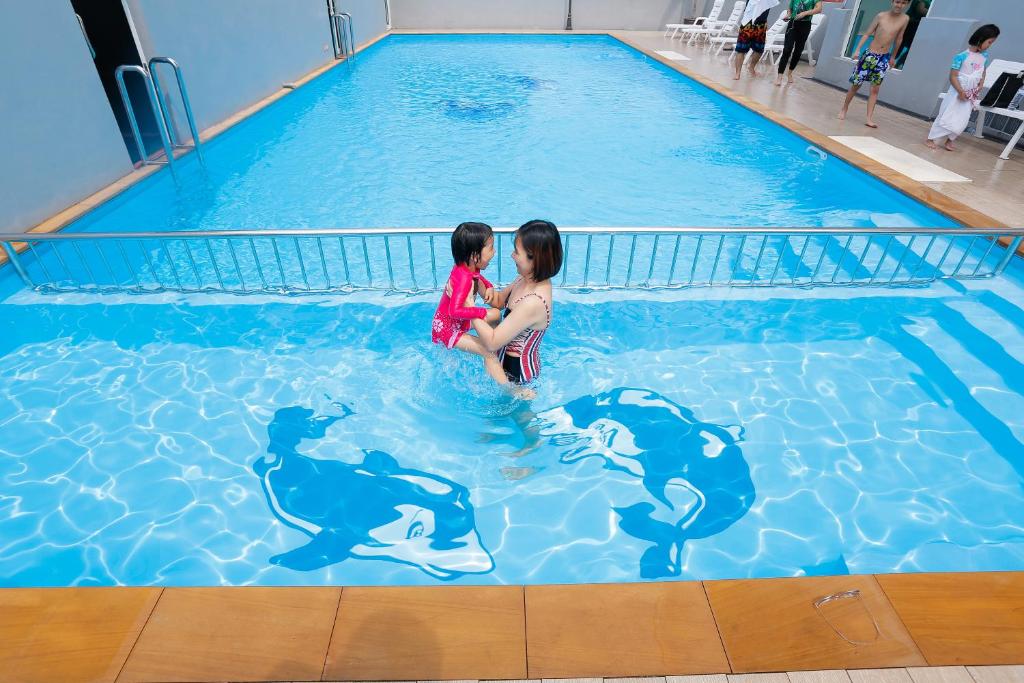 two children playing with dolphins in a swimming pool at Blue Orchids Hotel in Hat Yai