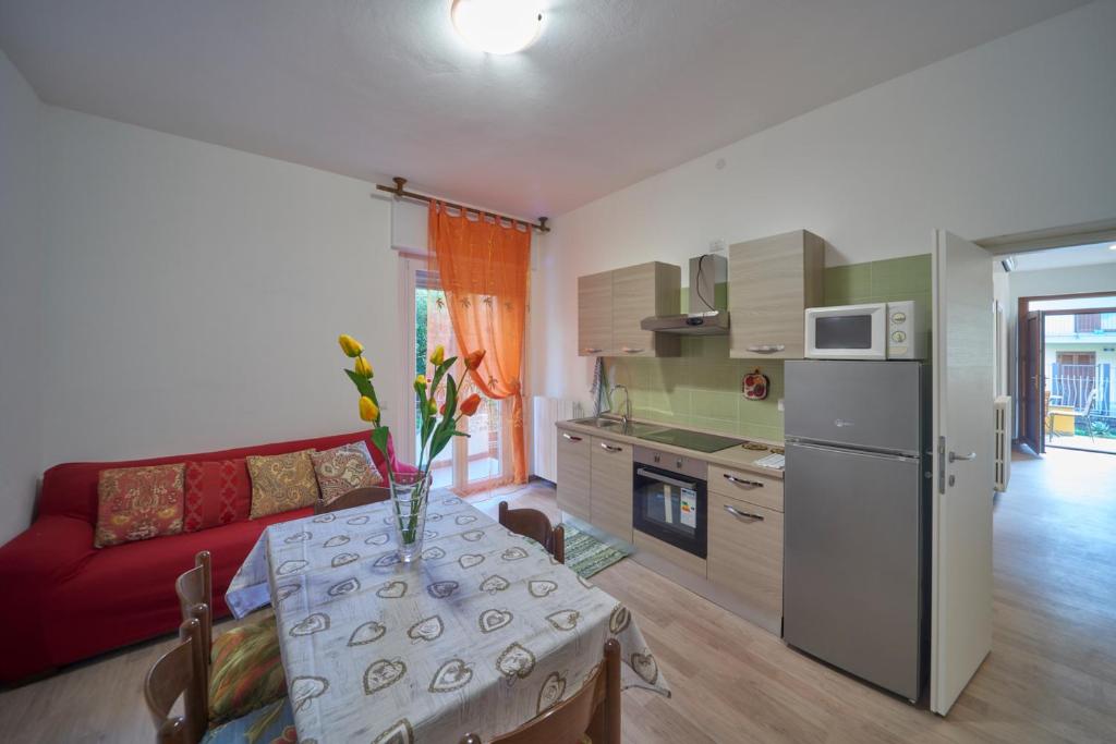 una cucina e un soggiorno con tavolo e divano rosso di Casa della nonna ad Abbadia Lariana