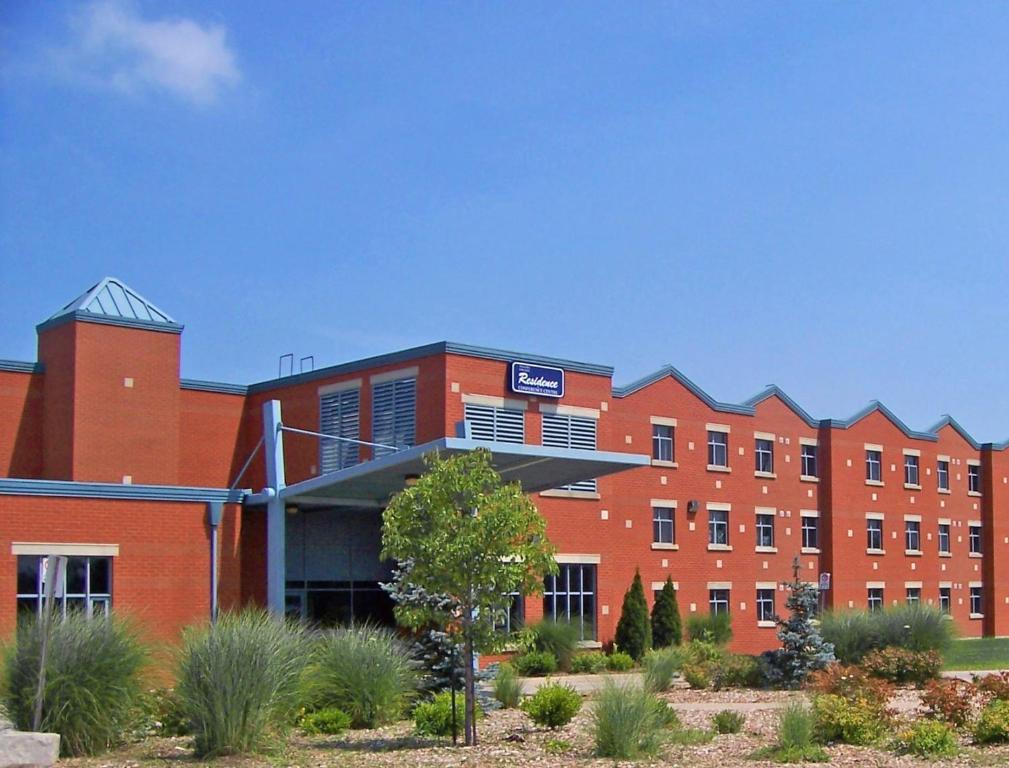 un gran edificio de ladrillo rojo con un cartel. en Residence & Conference Centre - Welland, en Welland