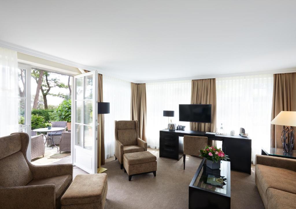 a living room with a couch and chairs and a television at Strandhotel Fontana in Timmendorfer Strand