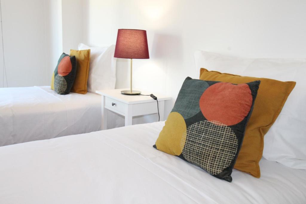 a bedroom with two beds and a table with a lamp at Parque das Nacoes River view ,free wifi in Lisbon
