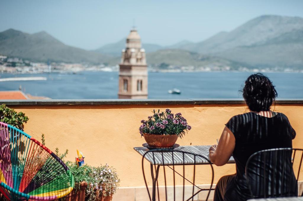 a woman sitting on a balcony looking at the water at B&B MilleQuattrocento in Gaeta