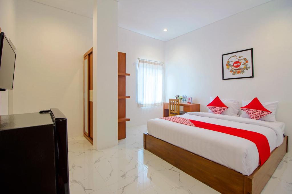 een slaapkamer met een bed met rode kussens en een televisie bij Super OYO 13I9 88 Exclusive Guesthouse in Yogyakarta