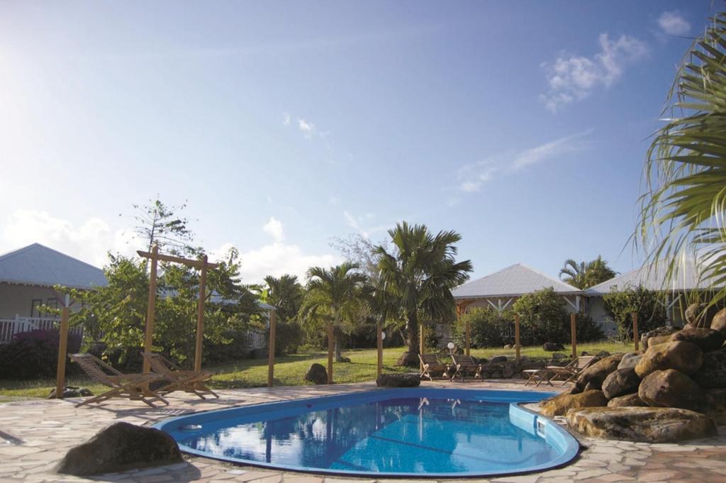 una gran piscina en un patio con rocas en Gîtes Mosaïques, en Sainte-Rose