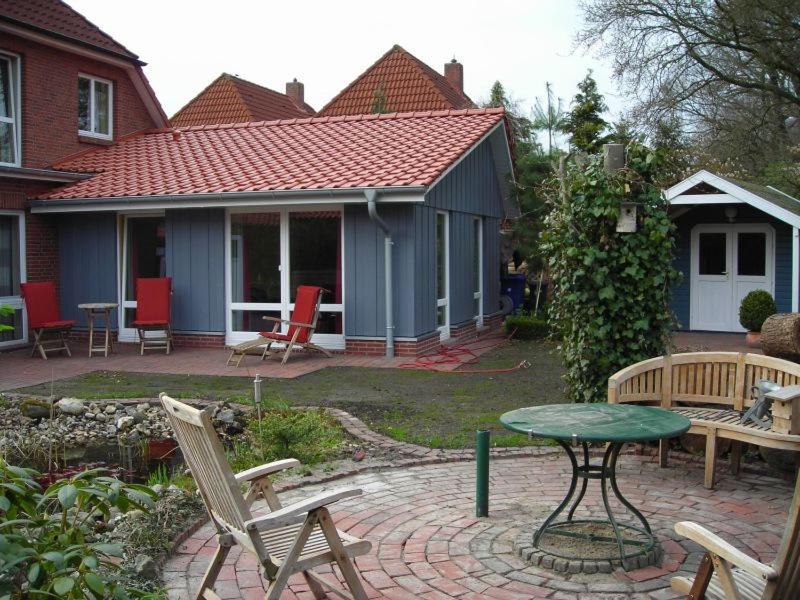 eine Terrasse mit Stühlen, einem Tisch und einem Haus in der Unterkunft Ferienwohnung Sommerhus in Wiefelstede