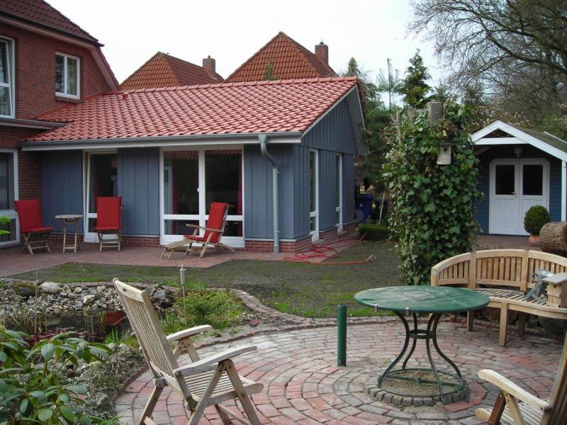 Un patio con sillas y una mesa y una casa. en Ferienwohnung Sommerhus, en Wiefelstede