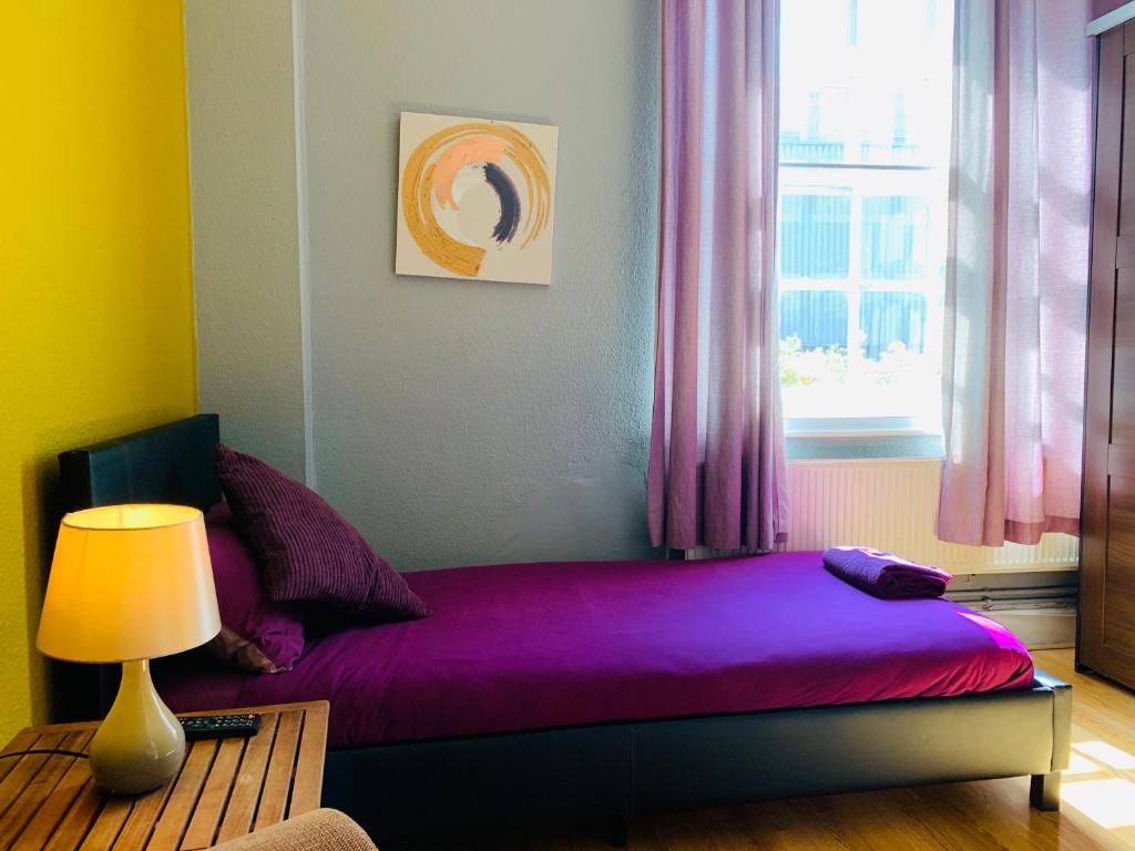 a bedroom with a purple bed with a window at Prince Arthur in London