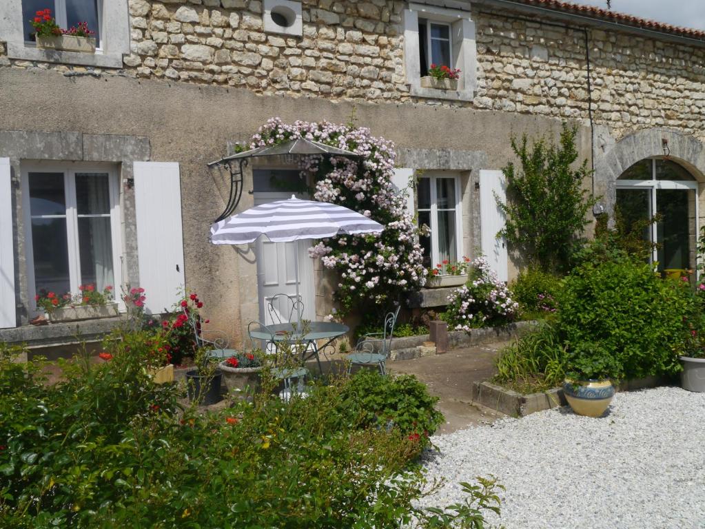 einen Garten mit einem Tisch und einem Sonnenschirm vor einem Gebäude in der Unterkunft gîte du luquet in Chazelles