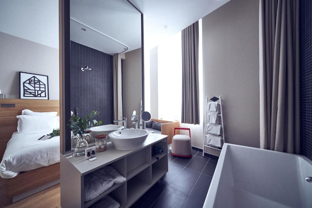 a bathroom with a sink and a tub and a bed at Maison Nô - Hôtel et Rooftop in Lyon