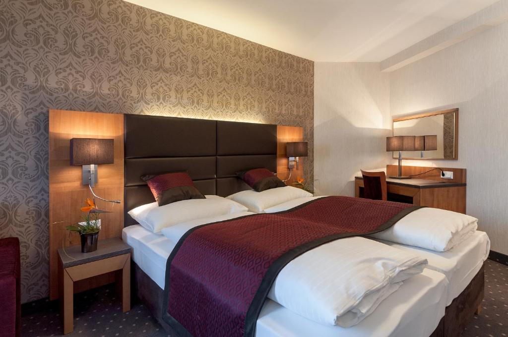 Pokój hotelowy z dużym łóżkiem z białymi poduszkami w obiekcie Club Hotel Cortina w Wiedniu