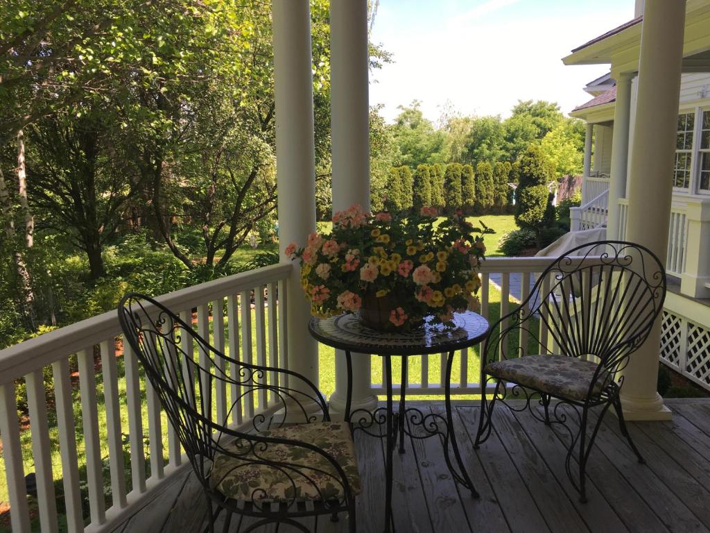 a porch with two chairs and a table with a vase of flowers at Williston Village Inn in Burlington
