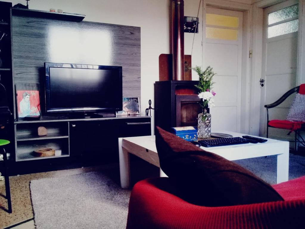 uma sala de estar com uma televisão e uma cadeira vermelha em Casa del Mar em Montevidéu