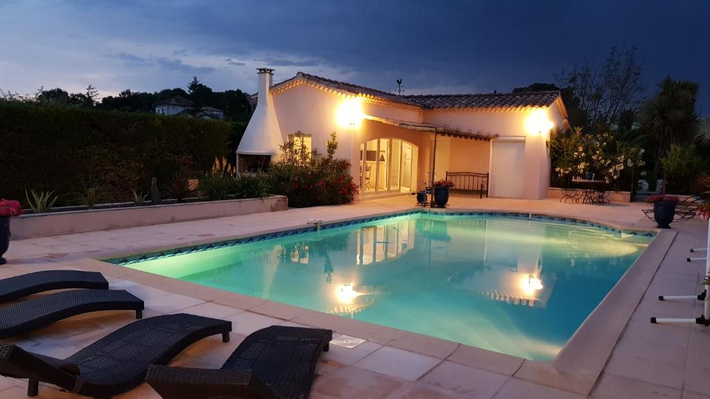 - une piscine avec 2 chaises et une maison dans l'établissement Gîte La Volière, à Cardet