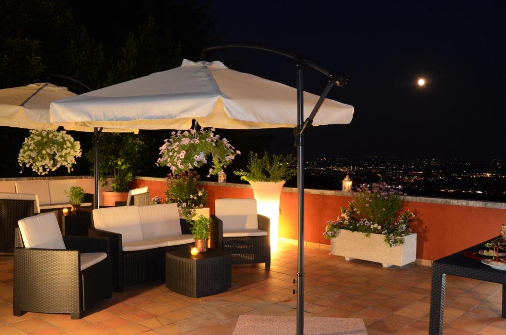een patio met een parasol, stoelen en een tafel bij B&b Ca'Baracca Bellavista in Bassano del Grappa