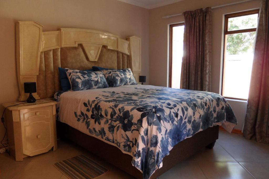 Schlafzimmer mit einem Bett mit einer blauen und weißen Bettdecke in der Unterkunft Garden Wing in Upington