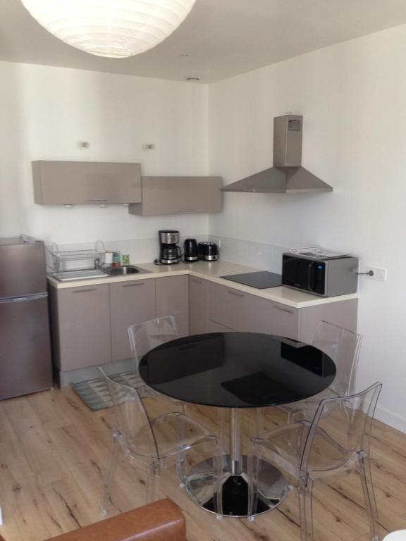 eine Küche mit einem schwarzen Tisch und Stühlen in der Unterkunft Joli appartement 40m2 entièrement équipé idéal pour location thermale ou saisonnier in Rochefort