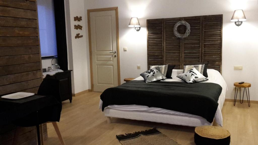 a bedroom with a large bed with black sheets and pillows at Le petit studio de l'espace bien être in Libin