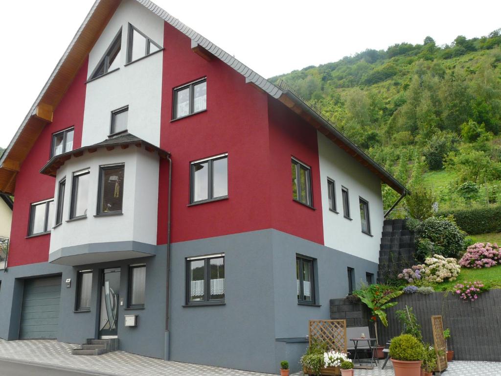 a red and white house with a hill in the background at Ferienwohnung Hermann in Sankt Aldegund