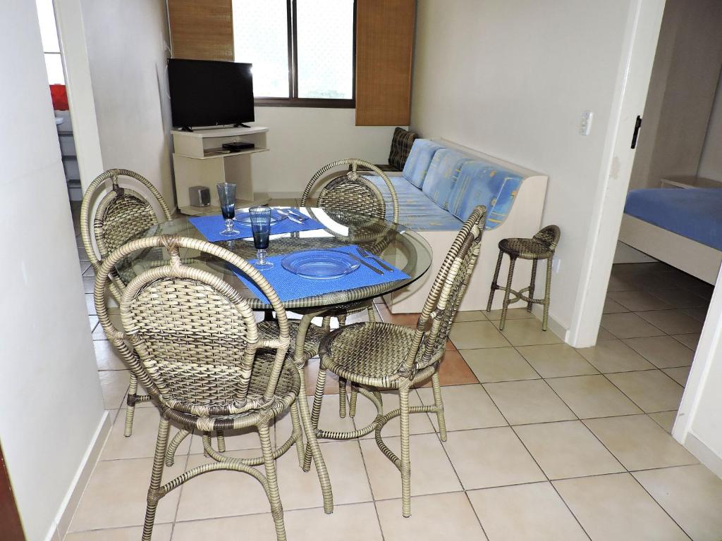 a dining room with a table and chairs and a couch at Condomínio Astúrias in Ubatuba