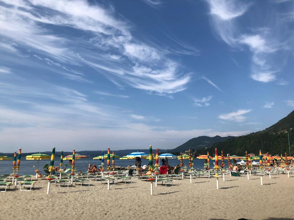 een groep stoelen en parasols op een strand bij Appartamento Lido fifty meters from the beach in Toscolano Maderno