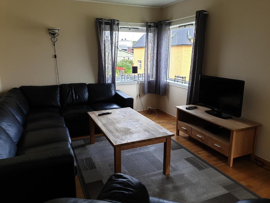 a living room with a couch and a table and a tv at Søndre Berg gate 20 Apartement in Vardø